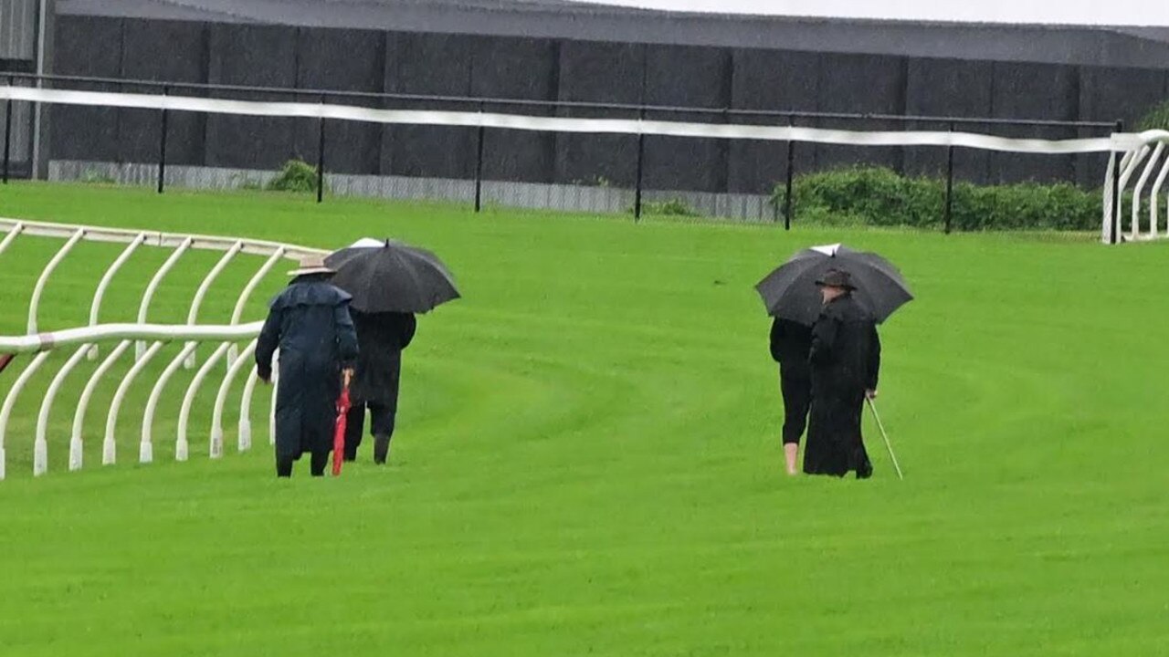 Stewards inspecting the Doomben track after heavy rain battered Brisbane ahead of the Doomben Cup. Picture: Grant Peters-Trackside Photography